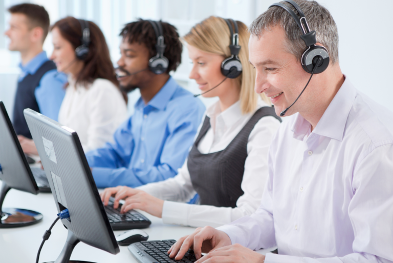 People at a help desk wearing headsets and working on computers for SMBs